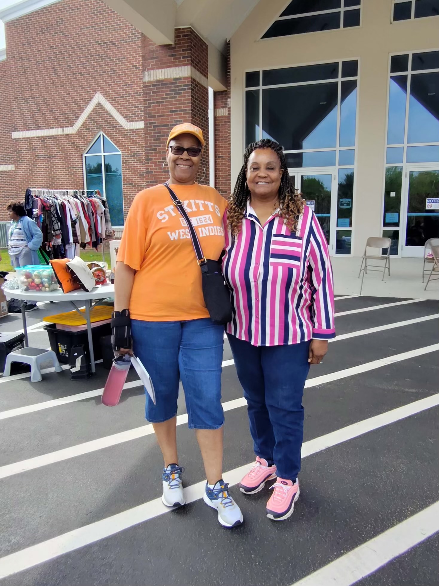 Two guests posing near the free clothing and goods tables